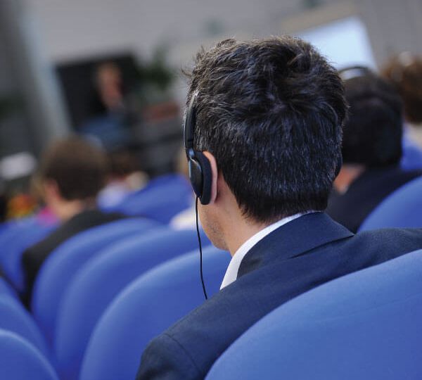 Attendee wearing headphones at a conference, using Skrivanek’s interpreting services for multilingual communication.