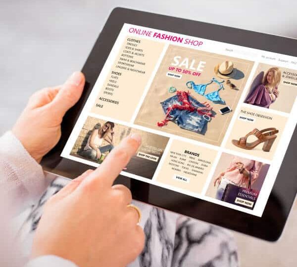 Person browsing a localized online fashion shop on a tablet, featuring global sale promotions, representing Skrivanek"s advanced localisation solutions.
