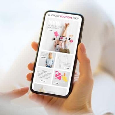 Skrivanek employee holding a smartphone with an online boutique interface, illustrating UX/UI in digital marketing.