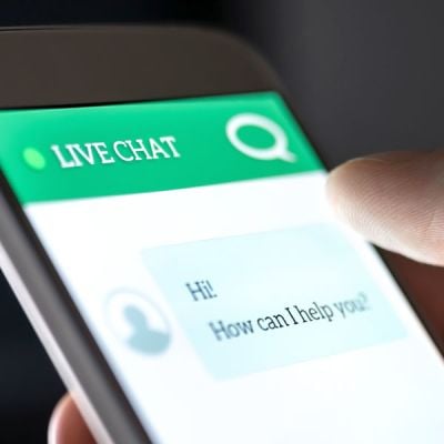 Smartphone mit einer Live-Chat-Schnittstelle, die digitale Interaktion und KI-gesteuerte Kommunikation durch die Chatbots von Skrivanek symbolisiert.