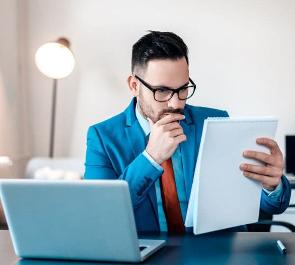 Ein professioneller Skrivanek-Übersetzer, der an einem Schreibtisch mit Laptop Dokumente überprüft, unterstreicht die Bedeutung der fachkundigen Übersetzungsdienste von Skrivanek Baltic.