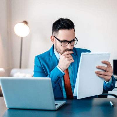 Ein professioneller Skrivanek-Übersetzer, der an einem Schreibtisch mit Laptop Dokumente überprüft, unterstreicht die Bedeutung der fachkundigen Übersetzungsdienste von Skrivanek Baltic.