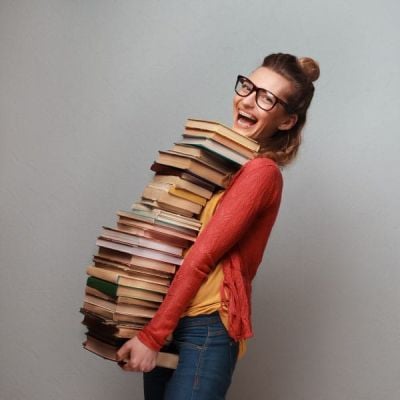 Skrivanek Baltic visual of a person carrying a tall stack of books, symbolizing the weight of proofreading responsibilities.