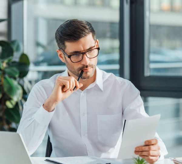 Professional evaluating documents at a desk in a modern office setting, representing the careful attitude towards top-notch translation services of a trusted translation agency like Skrivanek Baltic.