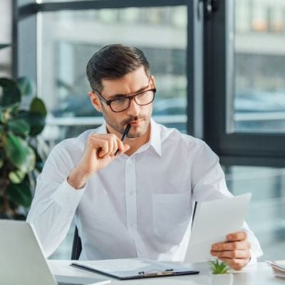 Professional evaluating documents at a desk in a modern office setting, representing the careful attitude towards top-notch translation services of a trusted translation agency like Skrivanek Baltic.
