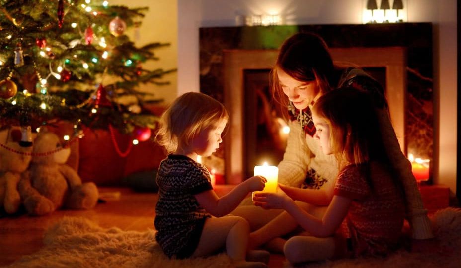 A family enjoying Christmas traditions by candlelight near a decorated tree and fireplace, reflecting the cultural diversity celebrated by Skrivanek Baltic.