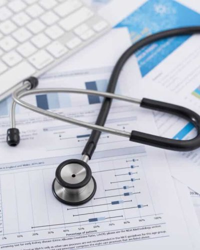 Fonendoskops uz medicīnisko atskaišu, grafiku un dokumentu izdrukām, blakus datora tastatūra – Skrivanek Baltic medicīniskā un dokumentu tulkošana.