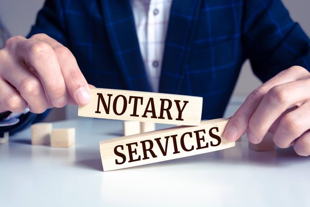Cilvēks tur koka klucīšus ar uzrakstu “Notary Services”, attēls vizualizē notariāli apliecinātu tulkojumu pakalpojumus Rīgā, ko nodrošina Skrivanek Baltic.