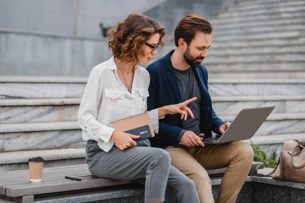 Kas veicina Latvijas pāreju uz interaktīvām platformām digitālajā vidē Divi profesionāļi strādā ar klēpjdatoru pilsētvidē, apspriežot digitālus risinājumus un interaktīvās platformas