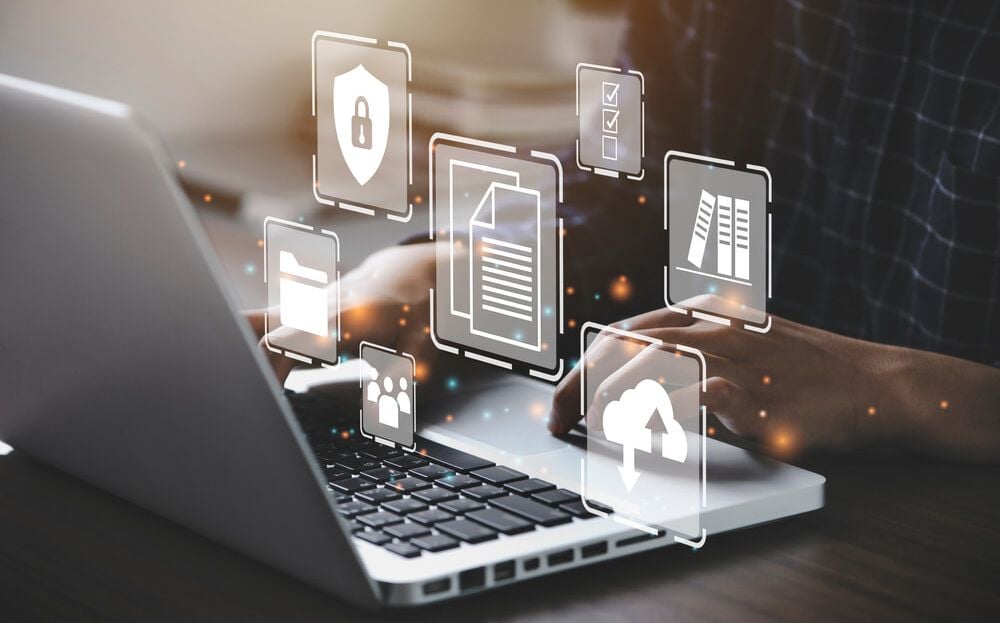 Tulkojuma datu drošība un konfidencialitāte – Skrivanek Baltic Cilvēks strādā pie klēpjdatora ar digitāliem drošības un datu aizsardzības ikonām, kas simbolizē tulkojuma datu konfidencialitāti.