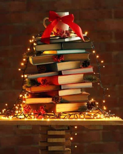 No grāmatām veidota eglīte ar gaismiņām kā ilgtspējīga Ziemassvētku dekorācija