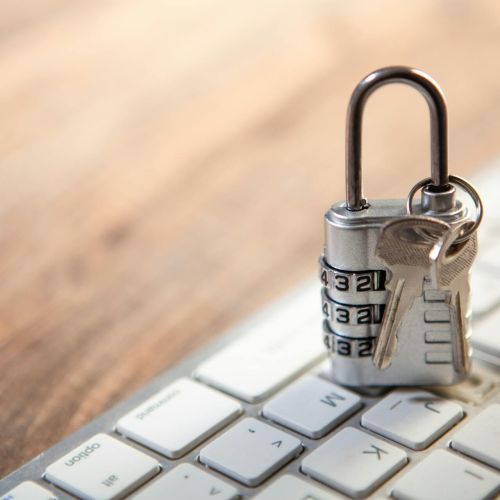 Valodas risku pārvaldība: semantiskās konsekvences nozīme – Skrivanek Baltic Metāliska kombinācijas piekaramā atslēga ar atslēgām uz datora tastatūras simbolizē datu aizsardzību un valodas riskus uzņēmumā, uzsverot semantiskās konsekvences un terminoloģijas pārvaldības nozīmi.