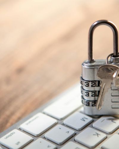 Metāliska kombinācijas piekaramā atslēga ar atslēgām uz datora tastatūras simbolizē datu aizsardzību un valodas riskus uzņēmumā, uzsverot semantiskās konsekvences un terminoloģijas pārvaldības nozīmi.