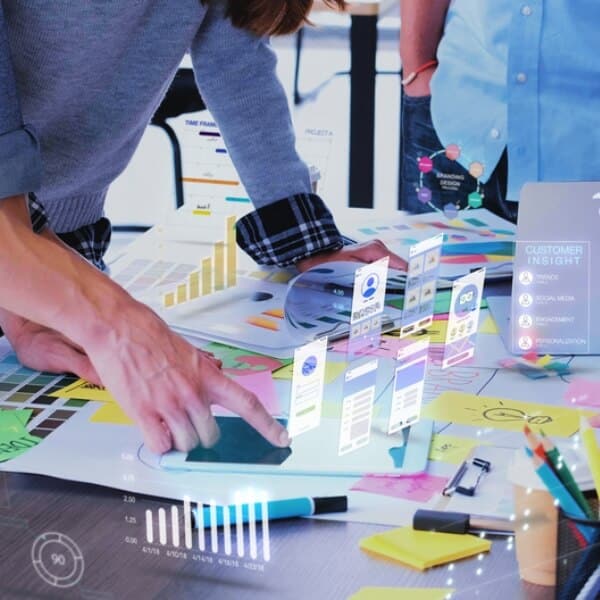 Cilvēks strādā pie klēpjdatora, veicot pierakstus kladē, kamēr priekšplānā redzami digitāli simboli, kas apzīmē informācijas struktūru, izglītību un datu uztveri; vizuāls tēls piekļūstamības principiem un skaidrai informācijas pasniegšanai digitālajā vidē