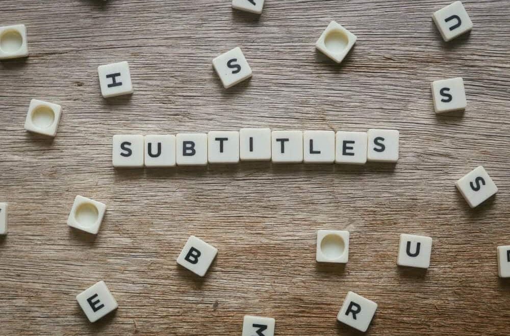 Uz koka galda izkārtoti burti, kas veido vārdu “Subtitles”, simbolizējot profesionālus subtitrēšanas un subtitru tulkošanas pakalpojumus video saturam.
