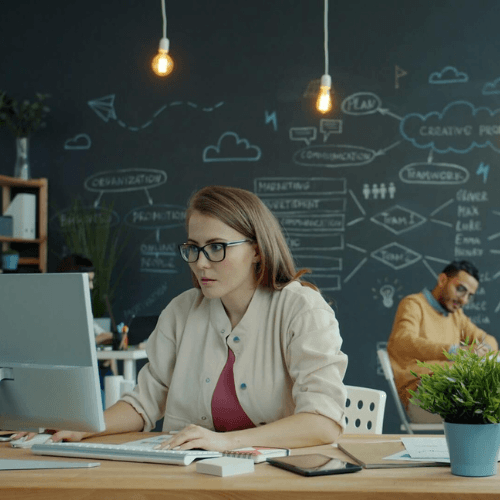 Speciāliste birojā strādā pie datora, pārskatot digitālu saturu un tekstus. Attēls ilustrē mākslīgā intelekta ietekmi uz tekstu, teksta rediģēšanu un satura kvalitātes pārbaudi.